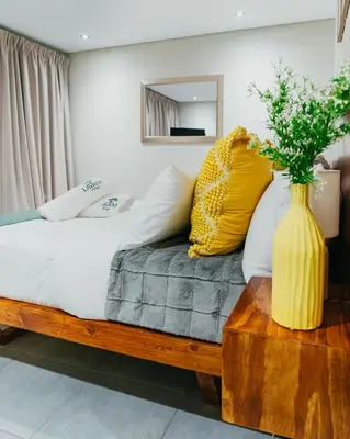 a bedroom with a bed with a yellow vase on a table at Lavani Lodge in Lerulaneng