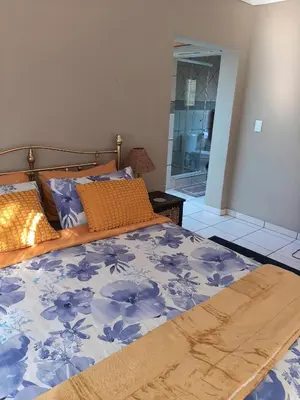 a bedroom with a bed with a blue and white comforter at Villa at Wekker in Pretoria