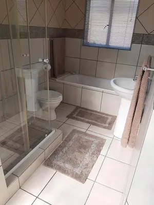 a bathroom with a shower and a toilet and a sink at Villa at Wekker in Pretoria