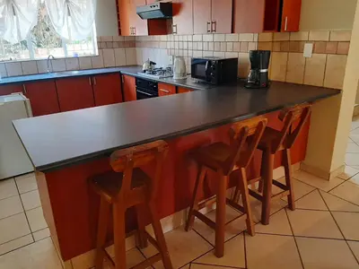 a kitchen with a counter and two stools at a bar at Villa at Wekker in Pretoria