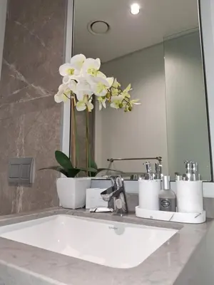 a bathroom with a sink and a mirror and flowers at Ellipse Kepler High-Rise 2-Bedroom en-suite Luxury Apartment in Midrand