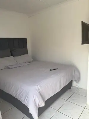 a bed in a bedroom with a remote control on it at Mohwelere Guest House in Pretoria