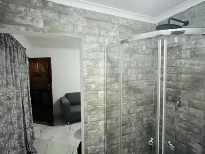 a bathroom with a glass shower with a chair at Mohwelere Guest House in Pretoria
