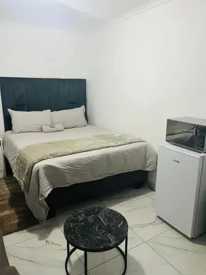 a bedroom with a bed with a stool and a table at Mohwelere Guest House in Pretoria