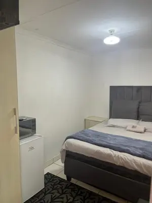 a bedroom with a bed and a white wall at Mohwelere Guest House in Pretoria