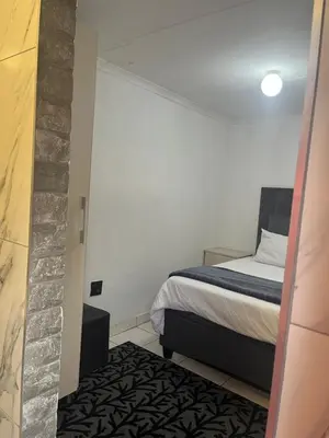 a bedroom with a bed and a brick wall at Mohwelere Guest House in Pretoria