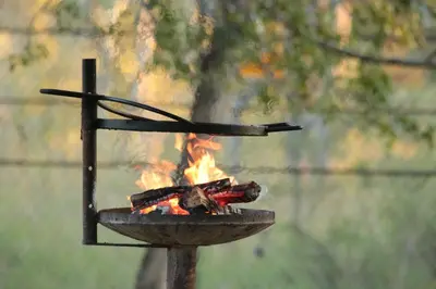 a grill with two sticks and a fire at Roodewal Bush Lodge in Mhalamhala