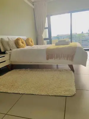 a bedroom with a bed and a rug and a window at Lake Villa Hartebees in Hartbeespoort