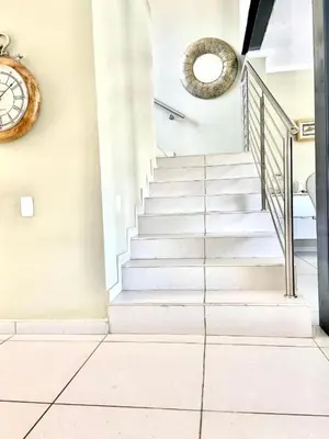 a staircase in a house with a clock on the wall at Lake Villa Hartebees in Hartbeespoort
