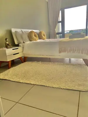 a bedroom with a bed and a white rug at Lake Villa Hartebees in Hartbeespoort