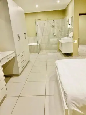 a large white bathroom with a bed and a shower at Lake Villa Hartebees in Hartbeespoort