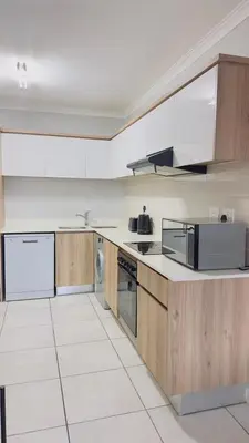 a kitchen with white appliances and wooden cabinets at House of sebo in Pretoria