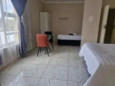 a room with a bed and a table and a chair at AB Lisi Accommodation in Pretoria