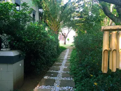 a garden path with rocks and trees and a fence at The Gables Middelburg MPU in Middelburg
