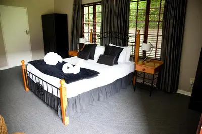 a bedroom with a bed with white sheets and pillows at The Gables Middelburg MPU in Middelburg