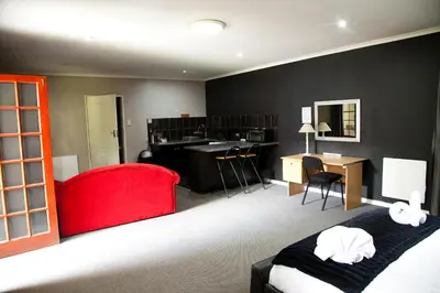 a hotel room with a bed and a red chair at The Gables Middelburg MPU in Middelburg