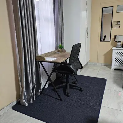 a desk and chair in a room with a window at The Luxury stay in Midrand
