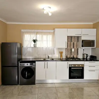 a kitchen with white cabinets and a black refrigerator at The Luxury stay in Midrand