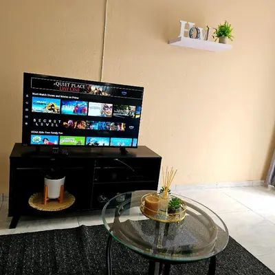 a living room with a glass table and a television at The Luxury stay in Midrand