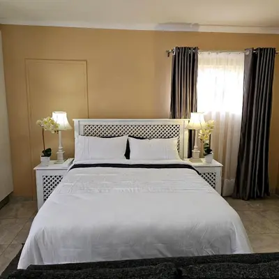 a bedroom with a large white bed with two lamps at The Luxury stay in Midrand