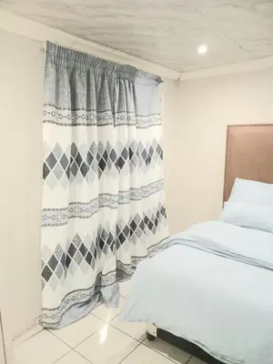 a bedroom with a bed and a curtain at Kama house in Pretoria
