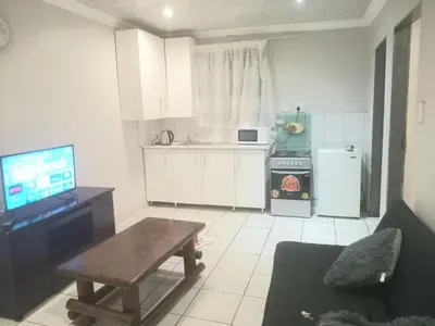 a kitchen with a couch and a table and a television at Kama house in Pretoria