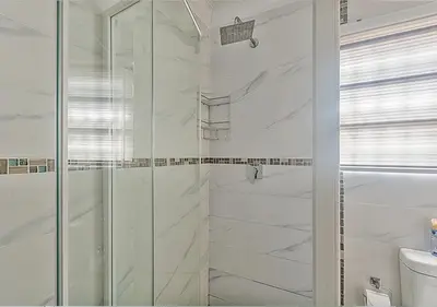 a bathroom with a shower with white marble walls at The Golden Place in Kempton Park