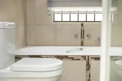 a bathroom with a toilet and a tub and a window at The Golden Place in Kempton Park