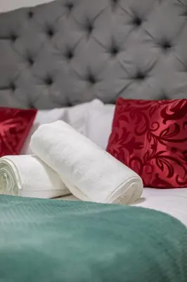 a rolled up towel on a bed with red pillows at The Golden Place in Kempton Park