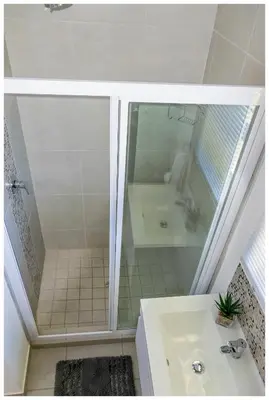 a white bathroom with a shower and a sink at Time out Main in Pretoria