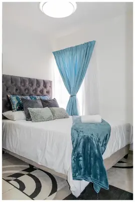 a bedroom with a bed with a blue curtain at Time out Main in Pretoria