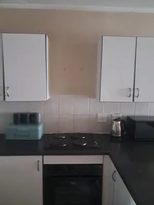 a kitchen with a black stove and white cabinets at Menlyn Place Oasis in Pretoria