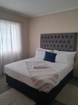 a bedroom with a large bed with a large headboard at Menlyn Place Oasis in Pretoria