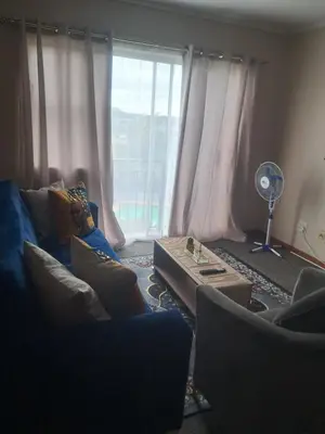 a living room with a blue couch and a window at Menlyn Place Oasis in Pretoria