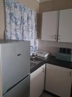 a kitchen with white cabinets and a sink and a curtain at Menlyn Place Oasis in Pretoria
