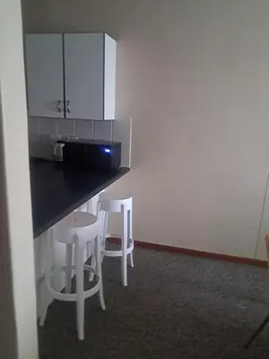 a kitchen with two white stools and a counter at Menlyn Place Oasis in Pretoria
