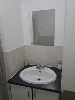 a bathroom with a white sink and a mirror at Menlyn Place Oasis in Pretoria