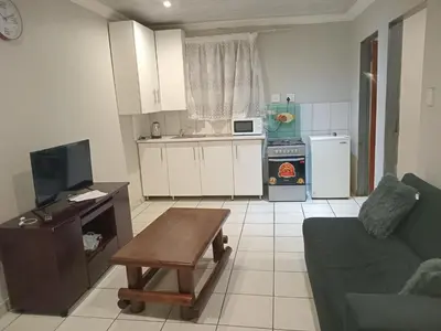 a kitchen and living room with a couch and a table at Kama B&B in Pretoria