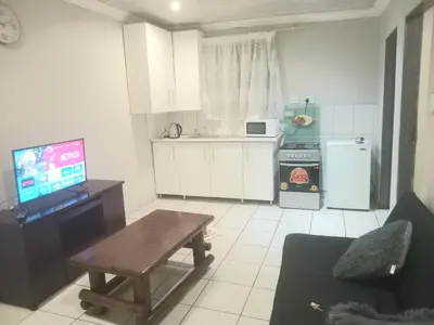 a kitchen with a table and a tv in a room at Kama B&B in Pretoria