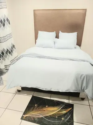 a bed with white sheets and a headboard in a room at Kama B&B in Pretoria