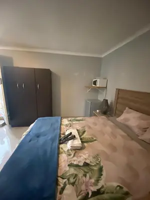 a bedroom with a bed with a floral blanket on it at Bennyz Guest House in Pretoria