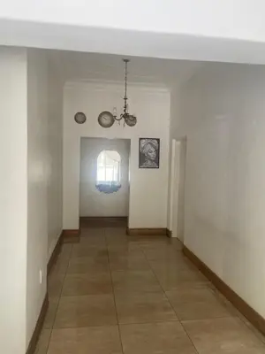 an empty hallway with a window and a chandelier at Bennyz Guest House in Pretoria