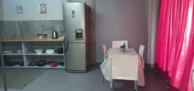 a refrigerator and a table in a room with a table and pink curtains at 329 on 30th Avenue Villieria Jimmy in Pretoria