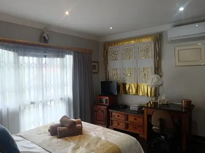 a bedroom with a bed and a desk and a window at AAA Accommodation in Pretoria