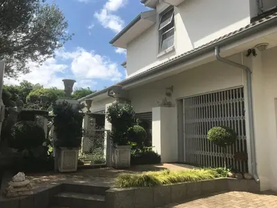 a white house with a gate and some bushes at AAA Accommodation in Pretoria