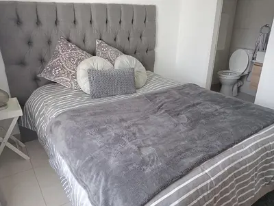 a bed with a gray headboard and pillows on it at Irene Moo Stay in Pretoria