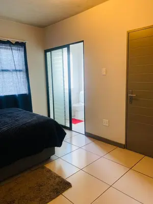 a bedroom with a bed and a door and a bathroom at Luxury Park Stays in Midrand