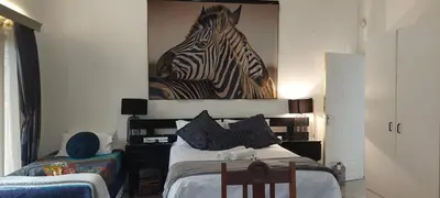 a bedroom with a bed with a picture of a zebra on the wall at Gemsbokrus in Marloth Park