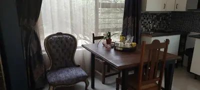 a kitchen with a wooden table and chairs and a window at Gemsbokrus in Marloth Park