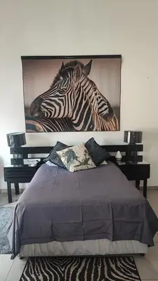 a bedroom with a picture of a zebra on the wall at Gemsbokrus in Marloth Park